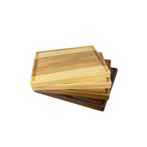 Set of stacked, handmade cutting boards on display, varying in wood species.